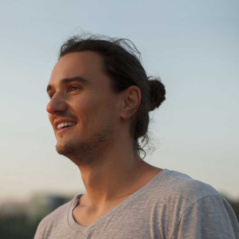 handsome-man-smiling-in-the-park-RKUHFQB